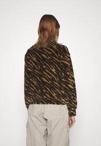 Brązowo-czarny dziergany sweter w wzory, o luźnym kroju i długich rękawach, z okrągłym dekoltem i miękką fakturą.