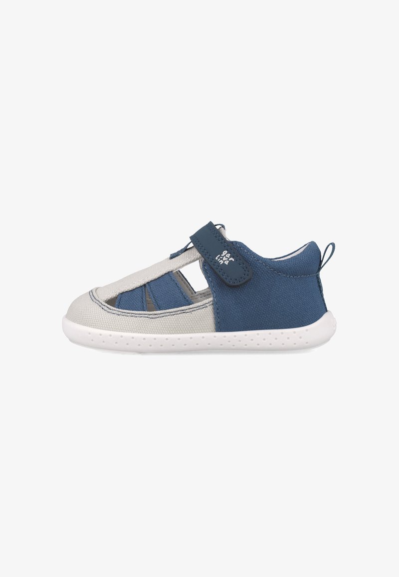 Zapato de lona transpirable en azul y gris con diseño recortado, correa de velcro y suela de goma blanca. Cuenta con una cinta en la parte trasera para facilitar su uso.