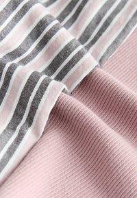 Dobladillos de tela suave con textura acanalada rosa y franjas horizontales adyacentes en rosa, blanco y gris sobre material tejido.