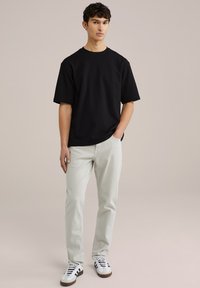 Černé bavlněné tričko s krátkým rukávem, kombinované s světle šedými džíny a bílými teniskami s černými pruhy. Čistý, ležérní vzhled.