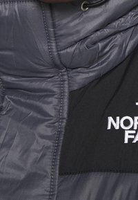 Kurtka puchowa w ciemnoszarym kolorze o pikowanej fakturze, z czarnym panelem i białym haftowanym logo "The North Face".