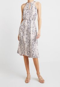 Sleeveless, knee-length dress in light pink with a black snake skin pattern, featuring a high neckline and a keyhole cutout detail.
