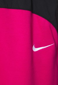 Nike sweatshirt med en livlig rosa kropp och en svart övre del. Inkluderar en vit broderad logotyp på vänster sida. Mjuk textur.