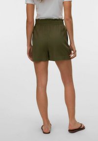 Pantalones cortos verdes, ligeros, con cintura elástica y bolsillos laterales, diseñados con un ajuste relajado; textura suave y forma simple.