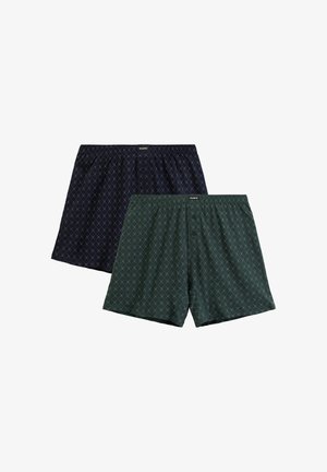 Dwie pary bokserek: jedna granatowa w wzór diamentowy, a druga zielona w podobnym wzorze, z guzikami z przodu i elastycznym paskiem w talii.