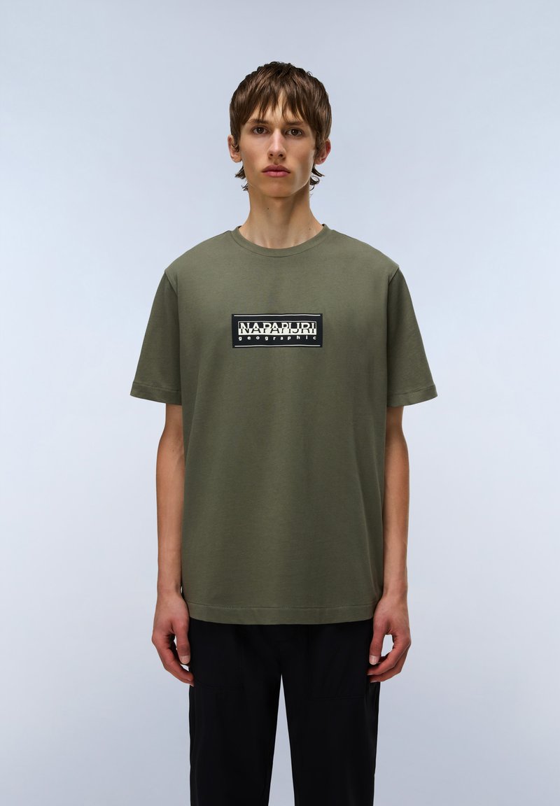 Olivengrøn bomulds t-shirt med korte ærmer og rund halsudskæring, som har et sort rektangulært logo print på fronten.