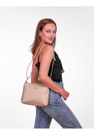 Béžová kožená kabelka přes rameno s hladkým povrchem, zipovým uzávěrem a nastavitelnými popruhy. Výrazné logo umístěné na přední straně.