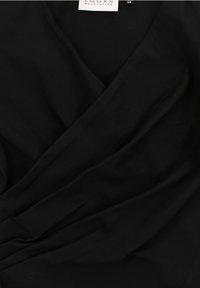 Zwarte wikkeltop van een zachte, lichte stof met een diepe V-halslijn en geplooide details bij de taille. Merkenlabel zichtbaar.