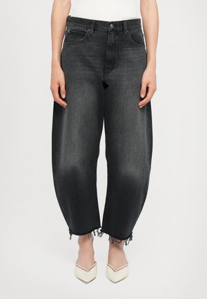 Black denim jeans with a loose fit, frayed hems, and five pockets. Paired with pointed white shoes. Textured fabric with slight fading.