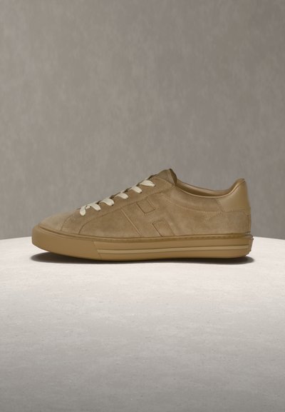 Baskets en daim beige avec talon en cuir lisse, lacets clairs contrastants, profil bas et semelle en caoutchouc ; dotées d'un logo minimaliste.