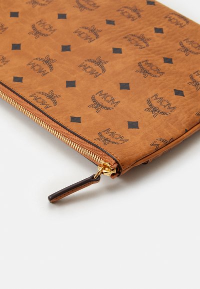 Pochette MCM marron avec logos noirs et motifs en forme de diamants, dotée d'une fermeture éclair dorée et d'une tirette marron foncé.