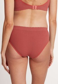 Culottes en ribbed rose avec une large ceinture élastique et une couverture moyenne. Texture lisse et ouvertures de jambe haute.