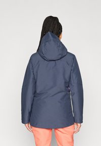 Ναυτικό αδιάβροχο μπουφάν με κουκούλα, με ελαφρώς φαρδιά εφαρμογή και λεία υφή. Η πίσω όψη δείχνει έναν απλό σχεδιασμό χωρίς στολίδια.