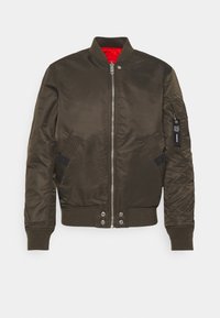 Olivgrön bomberjacka med dragkedja, ribbade ärmslut och nederkant, två sidofickor och en starkt röd foder. Har en dragkedjefick på ärmen.