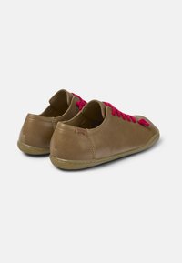 Sneaker in pelle marrone con lacci rosa; design a basso taglio, punta arrotondata, superficie testurizzata e suola in gomma flessibile. Cuciture decorative sul tallone.