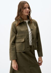 Olijfgroen suède jacket met een kraag, sluiting met knopen aan de voorkant, twee zijzakken en lange mouwen. Heeft een gladde textuur en een minimalistisch ontwerp.