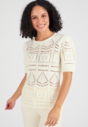 Suéter de punto en blanco roto, con mangas cortas y un diseño texturizado de trabajo abierto con patrones geométricos. Material suave y ligero.