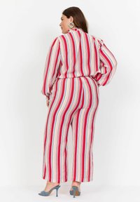 Salopetă cu dungi, în culorile roșu, alb și albastru, cu dungi verticale, având un guler înalt, mâneci lungi și pantaloni largi.