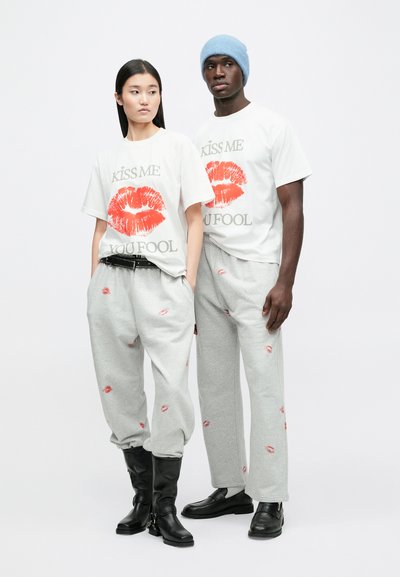 White t-shirts with red lipstick prints, gray sweatpants featuring kiss patterns, and black boots, complemented by a light blue beanie.