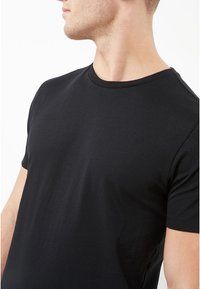 Svart kortärmad t-shirt i mjukt tyg, med en klassisk crew neck-design och en slät yta utan synliga mönster eller utsmyckningar.