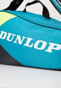 Dunlop Sporttasche aus türkisfarbenem Stoff mit schwarzen Akzenten. Verfügt über einen Reißverschluss oben und ein auffälliges weißes Logo an der Seite.
