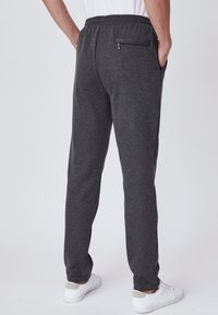Grijze sweatpants met een elastische tailleband, voorzien van zijzakken en een met rits afsluitbare achterzak. De stof ziet er zacht en casual uit.