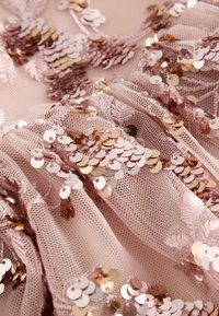 Lyserød tylstof prydet med rosaguld pailletter, med et lagdelt, tekstureret design og delikat blomsterbroderi.