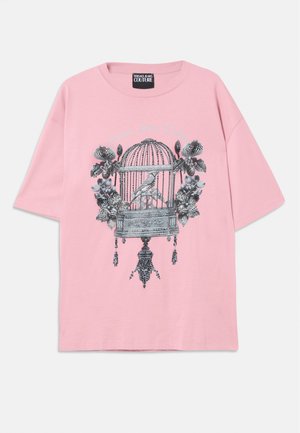 Lyserød t-shirt med korte ærmer, med sort-hvide motiver af fuglebur, fugl og blomster, samt "Versace Jeans Couture" tekst på forsiden.