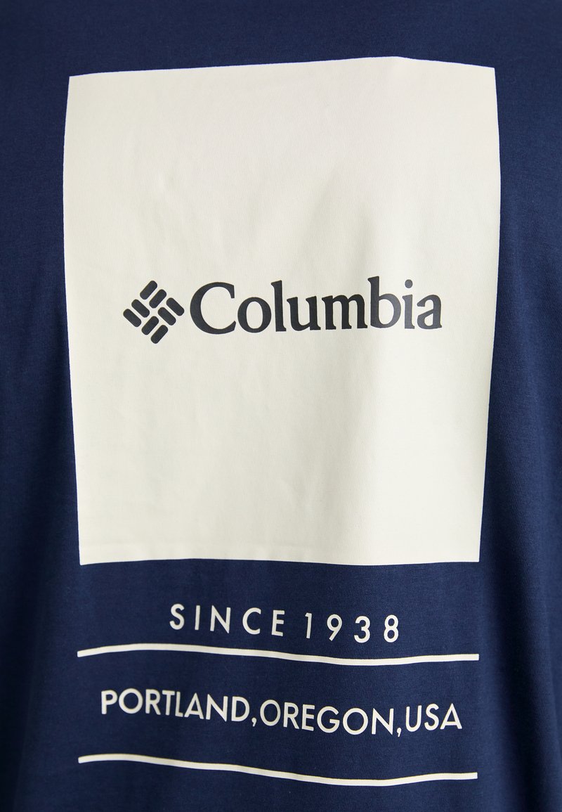 Marineblauwe t-shirt met een grote witte vierkante graphic met het "Columbia" logo en de tekst "SINCE 1938" en "PORTLAND, OREGON, USA" eronder.