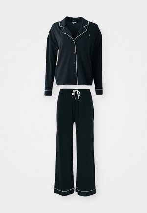 Black pajama set featuring a long-sleeve button-up shirt with white piping and matching pants with an elastic waistband and white drawstring.
