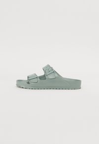 Sandale à glissière légère verte à deux brides, présentant un design ouvert à l'avant et une semelle texturée pour une meilleure adhérence. Fabriquée en matériau durable et flexible.