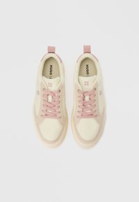 Sneakers with a cream canvas upper, pink suede accents, and matching laces. Features a white rubber sole and a logo on the side and tongue.