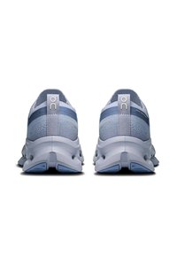 Baskets de sport bleu clair et gris avec un dessus texturé, bout rond et semelle flexible. Accents métalliques sur le talon et logo de la marque.