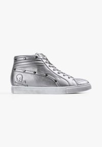 Zapatilla alta metálica plateada con un acabado de cuero suave, tachuelas negras y un diseño de calavera y huesos cruzados en el lado exterior.