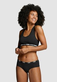 Schwarz Sport-BH und passende Unterwäsche mit kontrastierenden weißen "PUMA" Logo-Bändern. Der Stoff wirkt weich und dehnbar, mit einem taillierten Design.