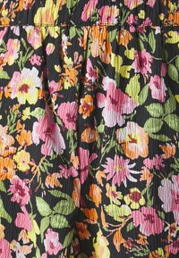 Svart stoff med en teksturert overflate som har et levende blomstermønster i rosa, gult og oransje, sammen med grønne blader.