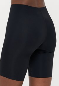 Sorte kompresjonsshorts laget av glatt stoff, med en kroppsnær design og midt på låret lengde, med en sømløs midjebånd.