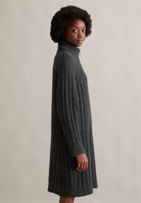 Donkergrijze geribde sweater jurk met een hoge kraag en lange mouwen, met een zachte textuur en een lengte die tot halverwege de dij valt.