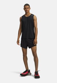 Top sportivo nero senza maniche e pantaloni corti, abbinati a scarpe da corsa nere e rosse. Il materiale sembra leggero, con un design elegante e una texture liscia.