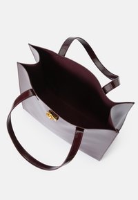 Saco tote de pele envernizada borgonha com duas alças, acessórios em dourado e um topo aberto que revela um interior semelhante a camurça. Acabamento liso e elegante.