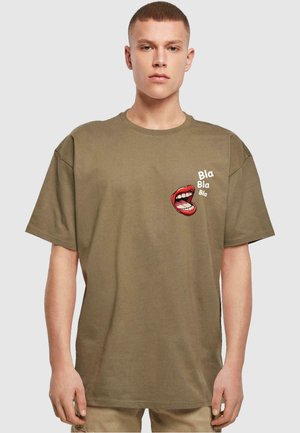 Olivenfarvet oversized t-shirt med et grafik af røde læber og teksten "Bla Bla Bla" i hvid. Ribbet tekstur, korte ærmer, rund hals.