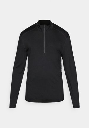 Pull noir à manches longues en tissu doux, avec un zip quart sur le devant et des panneaux contrastés aux épaules. Texture lisse et design ajusté.