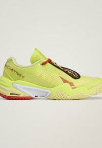 Fel geelgroene sportschoen met rode veters, zwarte en witte accenten op de zool en een "Repetitor +" label op het hielgedeelte.
