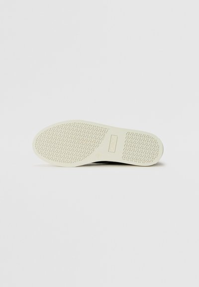 Schwarze Sneaker-Sohle mit einer strukturierten, weißen Gummibasis; verfügt über ein Logo und ein Zickzackmuster für Traktion. Einfaches, funktionales Design.