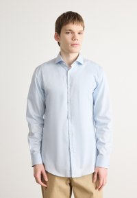 Light blue, long-sleeved button-up shirt made of cotton, featuring a pointed collar, slim fit, and straight hemline. Plain texture.