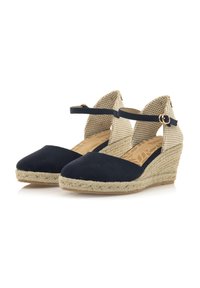 Marineblauwe suède wedge espadrilles hebben een geweven beige stoffen enkelband en een natuurlijke jute-gewikkelde hak, met een patroon in de binnenzool.