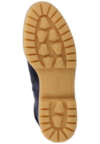 Semelle de chaussure en caoutchouc marron clair avec des motifs hexagonaux, des rainures profondes, et le nom de la marque "Gabor" embossé près du talon.