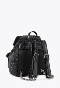 Czarny skórzany plecak z srebrnymi ćwiekami, regulowanymi paskami z srebrnymi klamrami oraz srebrnym łańcuszkiem u podstawy pasków.