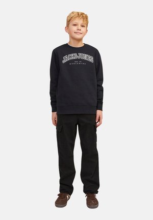 Felpa nera con testo bianco "JACK & JONES", abbinata a pantaloni cargo neri con tasche. Sneakers marroni completano l'outfit.