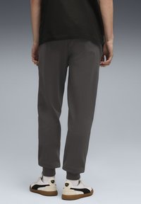 Grå sweatpants med en afslappet pasform, manchetter ved anklerne og sidelommer, parret med hvide og sorte sneakers og hvide ankelsokker.